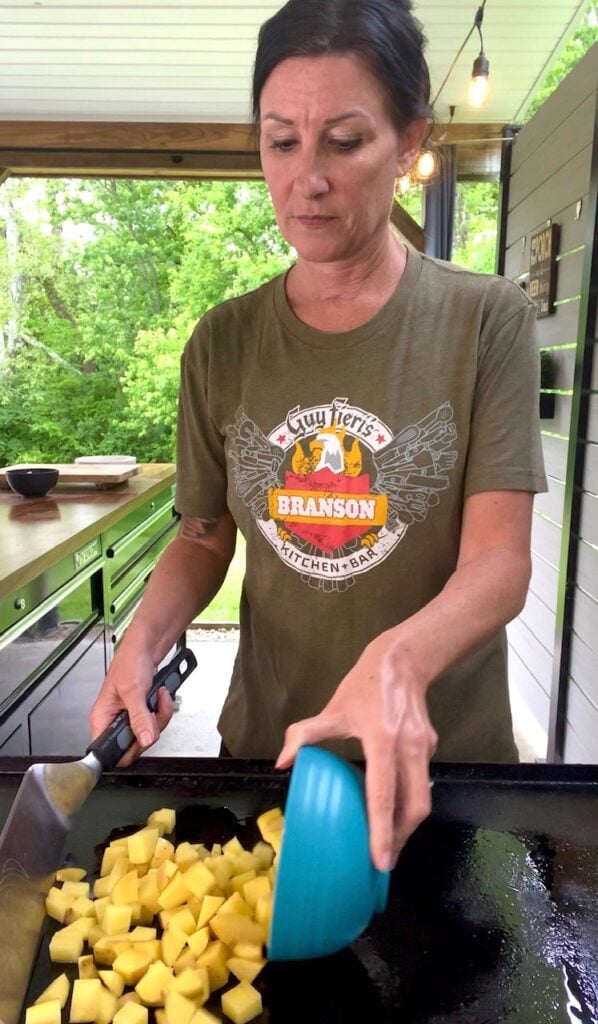 adding potatoes to the griddle