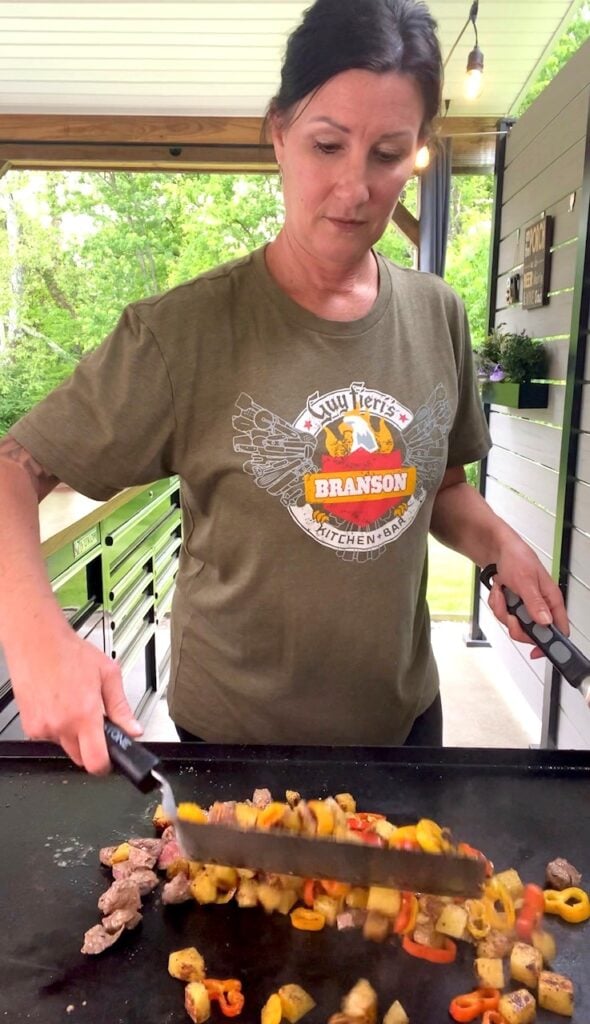 Mixing steak and potatoes on the griddle