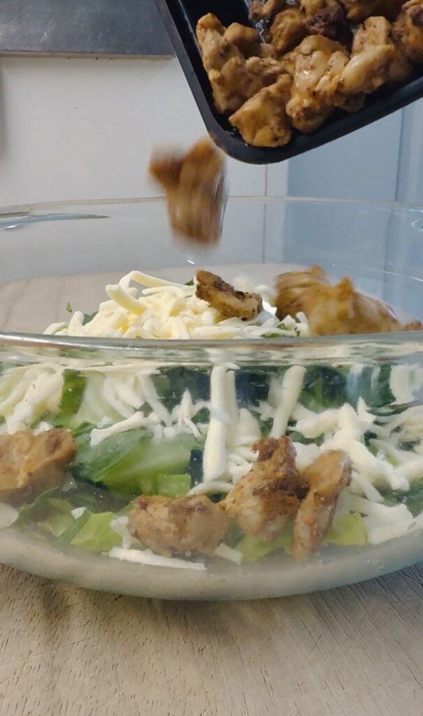 adding chicken to the salad
