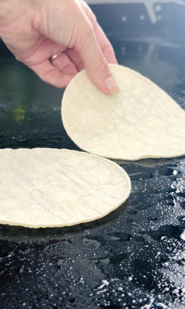adding corn tortilla to griddle