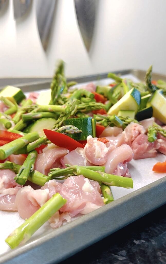 adding veggies to the sheet pan with chicken
